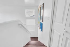 A staircase with white walls, wooden steps, and a window with blinds. - Family Home-mins from the LOOP with Hot Tub! (Tucson)