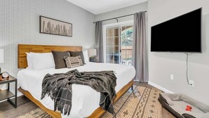 Habitació d'hotel amb un llit, una televisió, una finestra amb cortines i vista a l'exterior.