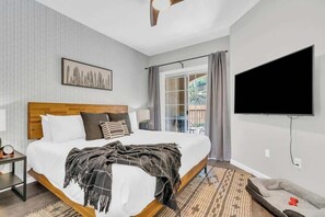 Ein Hotelzimmer mit Bett, Fernseher, Fenster mit Vorhängen und Blick ins Freie.