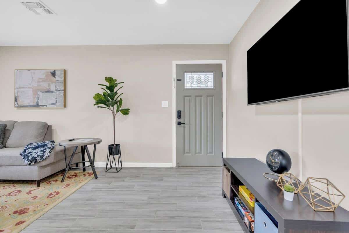 A living room with a sofa, a coffee table, a potted plant, a TV, and a bookshelf.