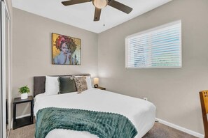 A bedroom with a bed, a ceiling fan, a window with blinds, and a painting on the wall. - Modern Central Location-10 mins from U of A (Tucson)