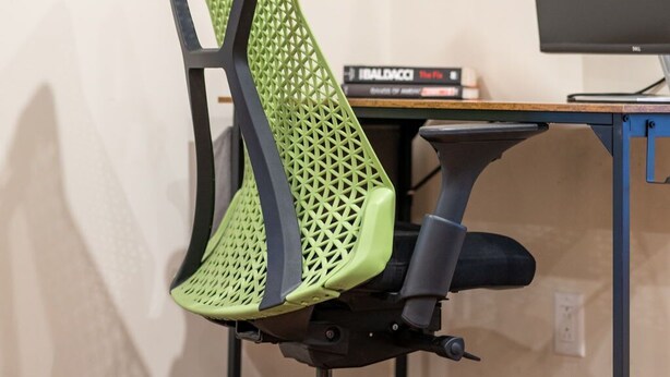 A green mesh office chair with wheels, a black desk, and a Dell monitor. - Famous Historic Big Blue House (Tucson)