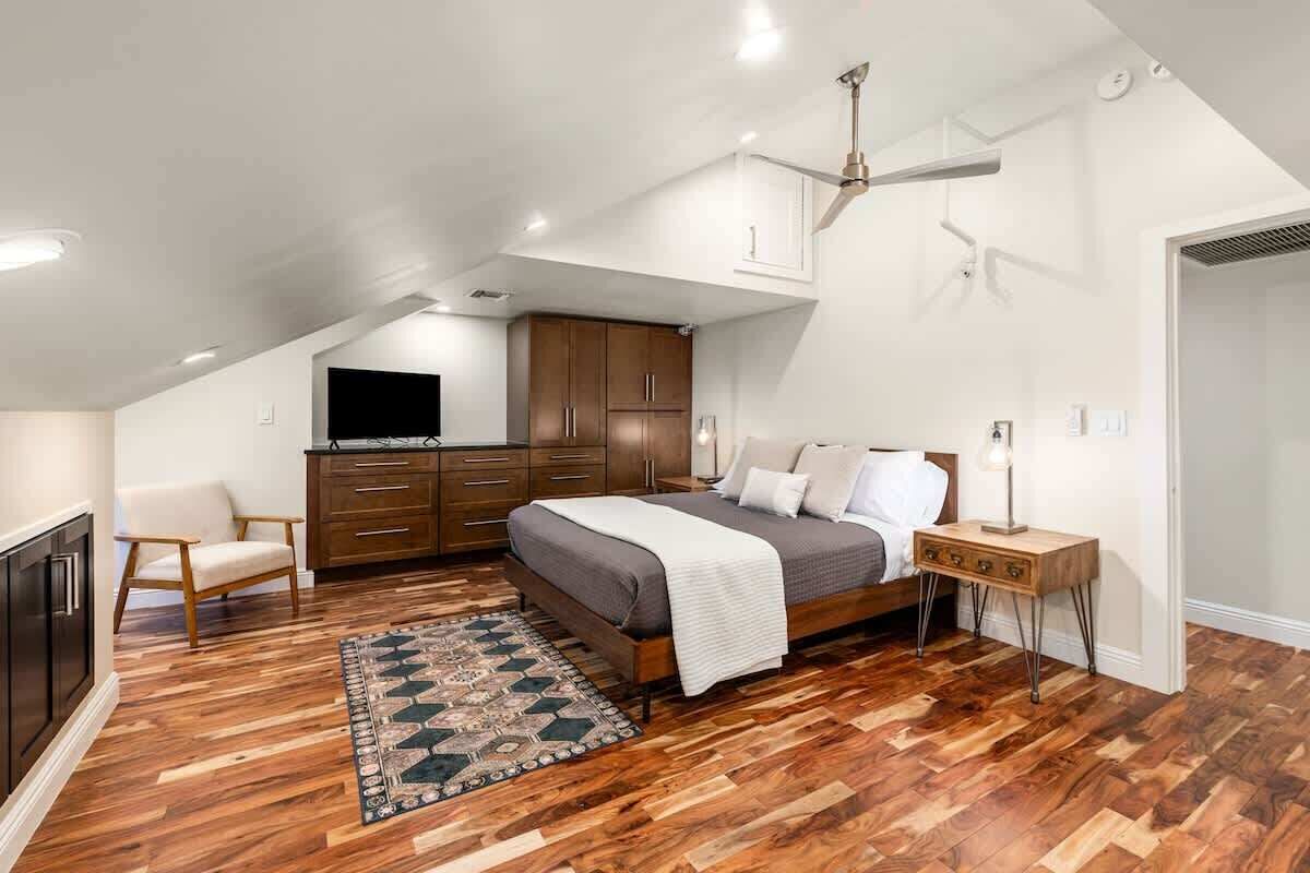 Une chambre à coucher comprenant un lit, une commode, un téléviseur, une chaise et une table de chevet.