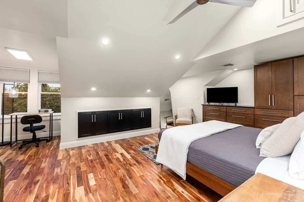 A bedroom with a bed, a desk, a chair, and a TV.
