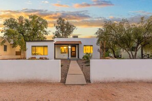 Una moderna casa a due piani con un ingresso centrale, ampie finestre e un vialetto che conduce alla porta.