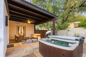 A hot tub under a wooden pergola with a patio chair and a table. - Renovated Adobe with Hot Tub-Close to U of A (Tucson)