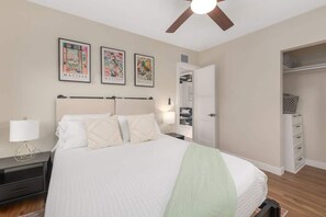 A bedroom with a bed, nightstands, a ceiling fan, and a walk-in closet. - Renovated Adobe with Hot Tub-Close to U of A (Tucson)
