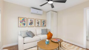 Ein Wohnzimmer mit einem weißen Sofa, einem runden Couchtisch und einem Deckenventilator.