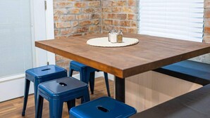 Ein Essbereich mit einem Holztisch, zwei blauen Hocker und einem Salz- und Pfefferset auf einer gewebten Tischmatte.