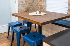 A dining area with a wooden table, two blue stools, and a salt and pepper set on a woven placemat. - Renovated Adobe with Hot Tub-Close to U of A (Tucson)
