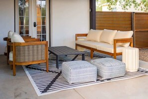 Un'area patio con un divano, una sedia, un tavolo e due poggiapiedi.