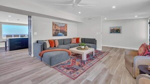 Una sala moderna con un sofá seccional gris, una mesa de centro y una alfombra estampada.
