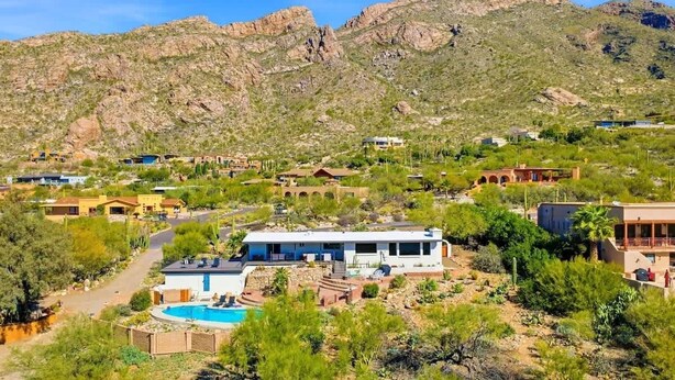 Zona residencial con casas, piscina y montañas al fondo.