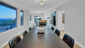 Un comedor moderno con una mesa grande, sillas y vistas amplias a través de grandes ventanales.