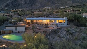 Una casa moderna con piscina, rodeada de un paisaje rocoso y montañas.