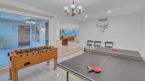 A modern room with a foosball table, ping pong table, and a chandelier. - Desert Vibes with Pool, Sauna & Game Room! (Tucson)