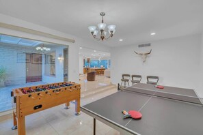 Ein modernes Zimmer mit Tischfußball, Pong-Tisch und einer Kronleuchter.