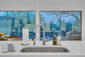 A modern kitchen with a stainless steel sink, a faucet, and a bottle labeled 'DISHES HAND'. - Desert Vibes with Pool, Sauna & Game Room! (Tucson)