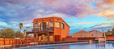 Une maison moderne à deux étages, dotée d’une piscine, d’un patio couvert et d’une clôture en bois.