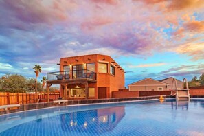 A modern two-story house with a swimming pool, a covered patio, and a wooden fence. - Modern Loft with Pool & Hot Tub-Views! (Tucson)