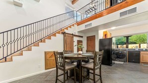 A spacious kitchen with a dining area, a staircase, and a laundry area. - Modern Loft with Pool & Hot Tub-Views! (Tucson)