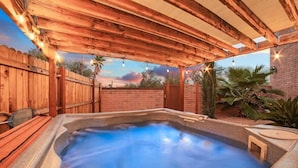 A hot tub under a wooden pergola with string lights, surrounded by a wooden fence and palm plants. - Modern Loft with Pool & Hot Tub-Views! (Tucson)