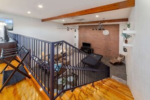 Amplia sala de estar con escaleras, chimenea y televisor.