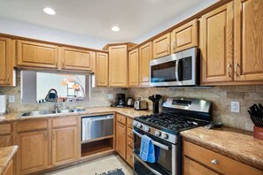 A kitchen with wooden cabinets, stainless steel appliances, and a granite countertop. - Pool & Pet Friendly-Walk to Udall Park (Tucson)