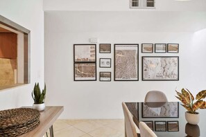 A room with a dining table, chairs, a potted plant, and framed cityscape photographs on the wall. - Pool & Pet Friendly-Walk to Udall Park (Tucson)