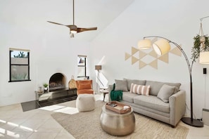 A modern living room with a fireplace, a sofa, a coffee table, and a floor lamp. - Pool & Pet Friendly-Walk to Udall Park (Tucson)