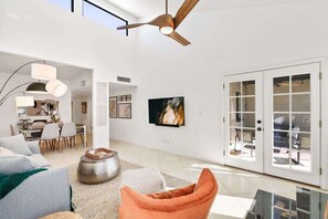 A spacious living area with a ceiling fan, a dining area with chairs, a sofa, and a TV mounted on the wall. - Pool & Pet Friendly-Walk to Udall Park (Tucson)