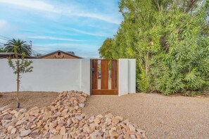 A modern building with a white exterior, a wooden door, and a gravel pathway leading to it. - The Hidden Gem-5 mins to U of A with Hot Tub (Tucson)