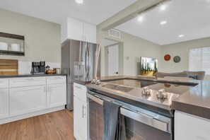 A modern kitchen with white cabinetry, stainless steel appliances, and a wooden countertop. - The Hidden Gem-5 mins to U of A with Hot Tub (Tucson)