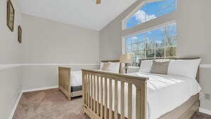 A bedroom with a large window, a crib, a bed, and a ceiling fan. - Catalina Mountain Views with Pool (Tucson)
