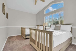 A bedroom with a large window, a crib, a bed, and a ceiling fan. - Catalina Mountain Views with Pool (Tucson)