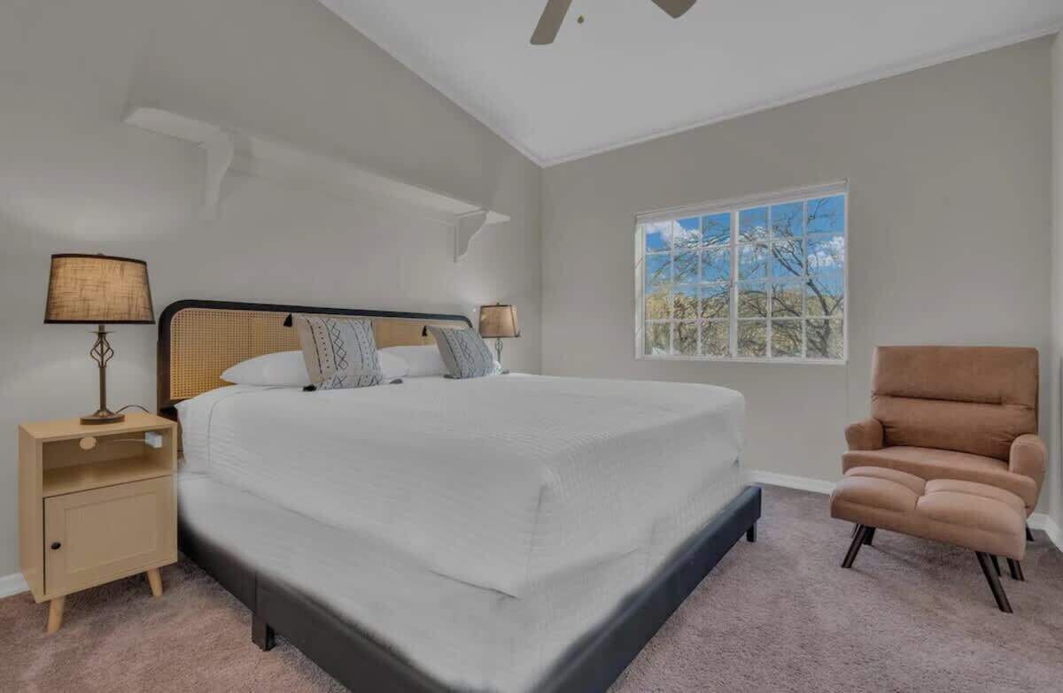 Een slaapkamer met een groot bed, nachtkastjes, een stoel en een raam met uitzicht.