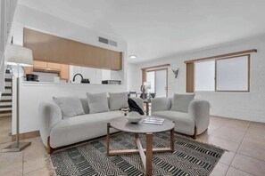 A modern living room with a sofa, coffee table, and patterned rug. - Trendy Cozy Townhome with Pool (Tucson)