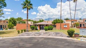 A building with a brick facade, a covered entrance, and a parking lot. - Trendy Cozy Townhome with Pool (Tucson)