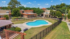 Un quartier résidentiel doté d’une piscine, de maisons aux toits recouverts de tuiles rouges et d’une cour clôturée.