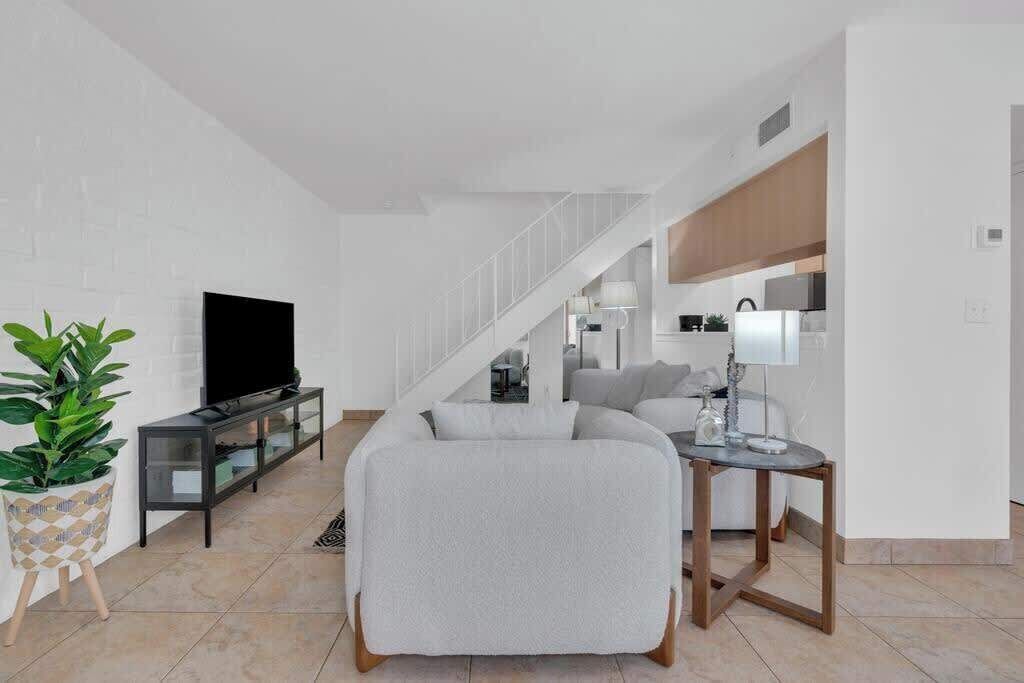 Ett modernt vardagsrum med en soffa, en tv och en trappa som leder upp till en matplats.