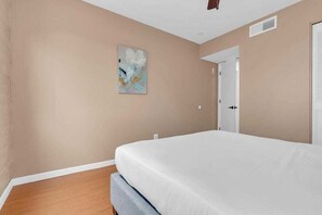 A bedroom with a bed, a door, and a wall-mounted artwork. - Trendy Cozy Townhome with Pool (Tucson)
