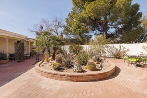 A courtyard with a circular brick planter filled with various cacti and desert plants, surrounded by outdoor furniture. - Sonoran Paradise with Pool (Tucson)