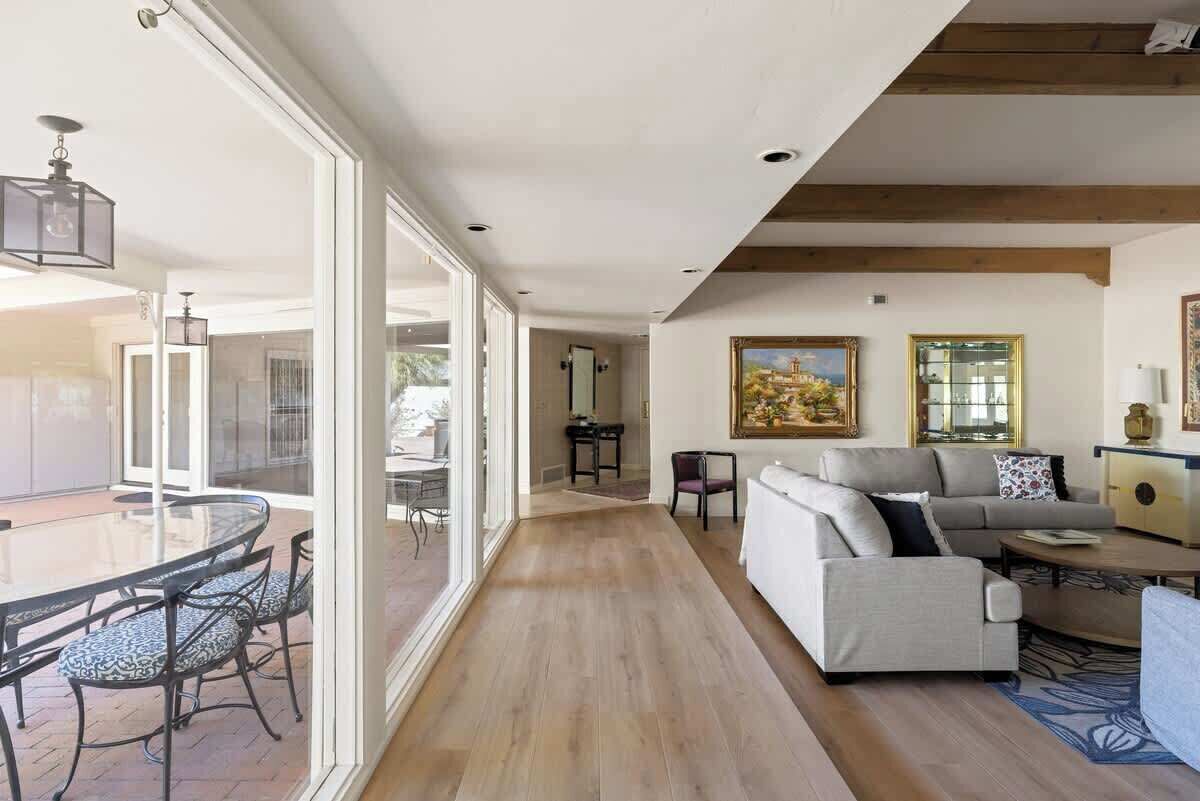 A spacious living area with a glass dining table, a sofa, and a painting on the wall.