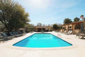 A rectangular swimming pool with lounge chairs and umbrellas, surrounded by trees and buildings. - Sonoran Paradise with Pool (Tucson)