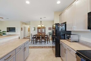 A modern kitchen with a dining area, featuring a refrigerator, oven, and a dining table with chairs. - Quiet Desert Haven- 5 mins to Starr Pass (Tucson)