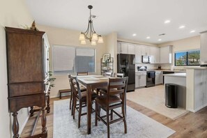 A modern kitchen with a dining area, wooden furniture, and a chandelier. - Quiet Desert Haven- 5 mins to Starr Pass (Tucson)