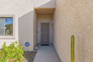 A building entrance with a door, a small garden, and a sign. - Quiet Desert Haven- 5 mins to Starr Pass (Tucson)