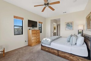 A bedroom with a bed, a wooden dresser, a ceiling fan, a TV, and a painting on the wall. - Quiet Desert Haven- 5 mins to Starr Pass (Tucson)