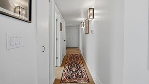 A hallway with a patterned rug, white walls, and wall-mounted lights. - Catalina Foothills Luxe Retreat with Heated Pool! (Tucson)