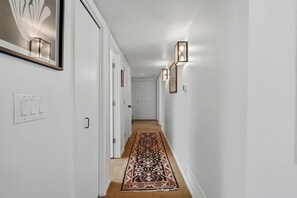 A hallway with a patterned rug, white walls, and wall-mounted lights. - Catalina Foothills Luxe Retreat with Heated Pool! (Tucson)
